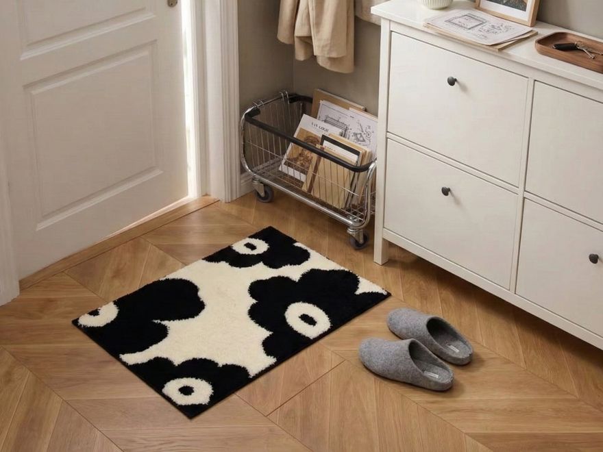 Alfombra de flores en blanco y negro junto a la puerta de entrada, con zapatillas y un mueble zapatero